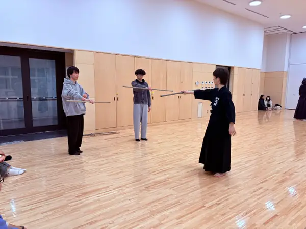 先輩部員から杖の基本的な構え方を教わる体験者たち